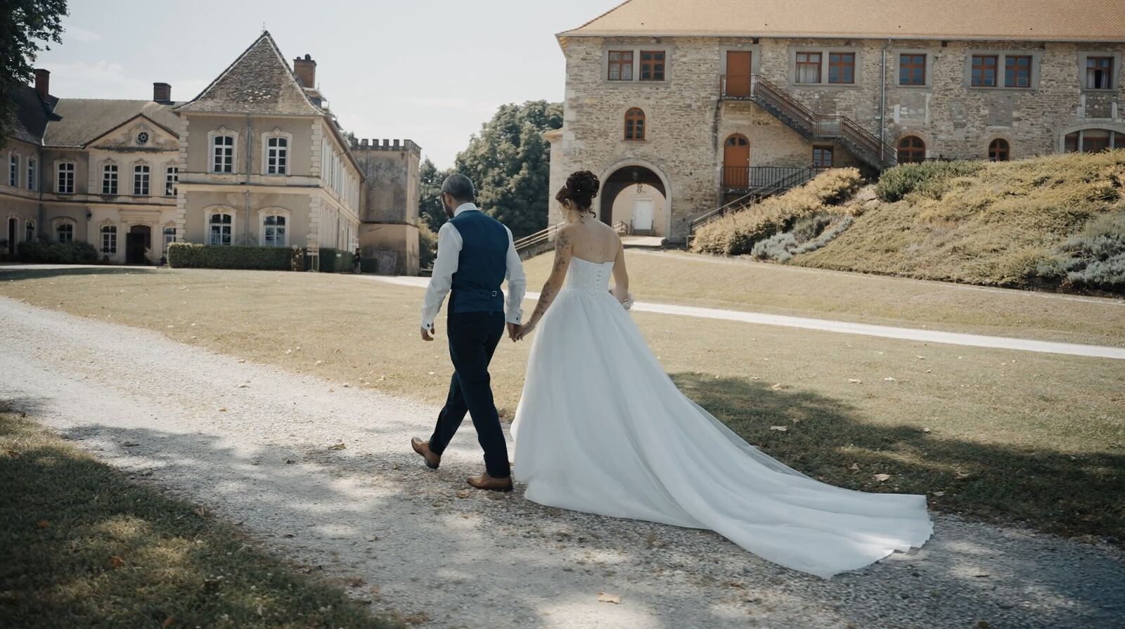 Les mariés marchent main dans la main devant un château