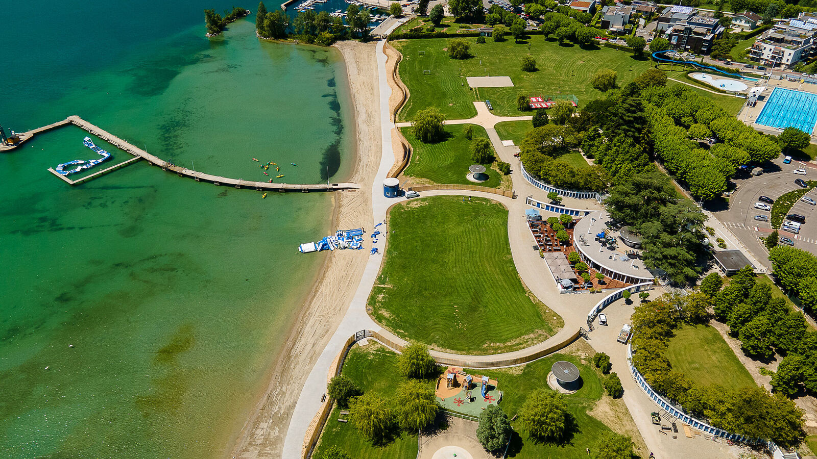 Plage et parc au bord d'un lac turquoise, vue de drone