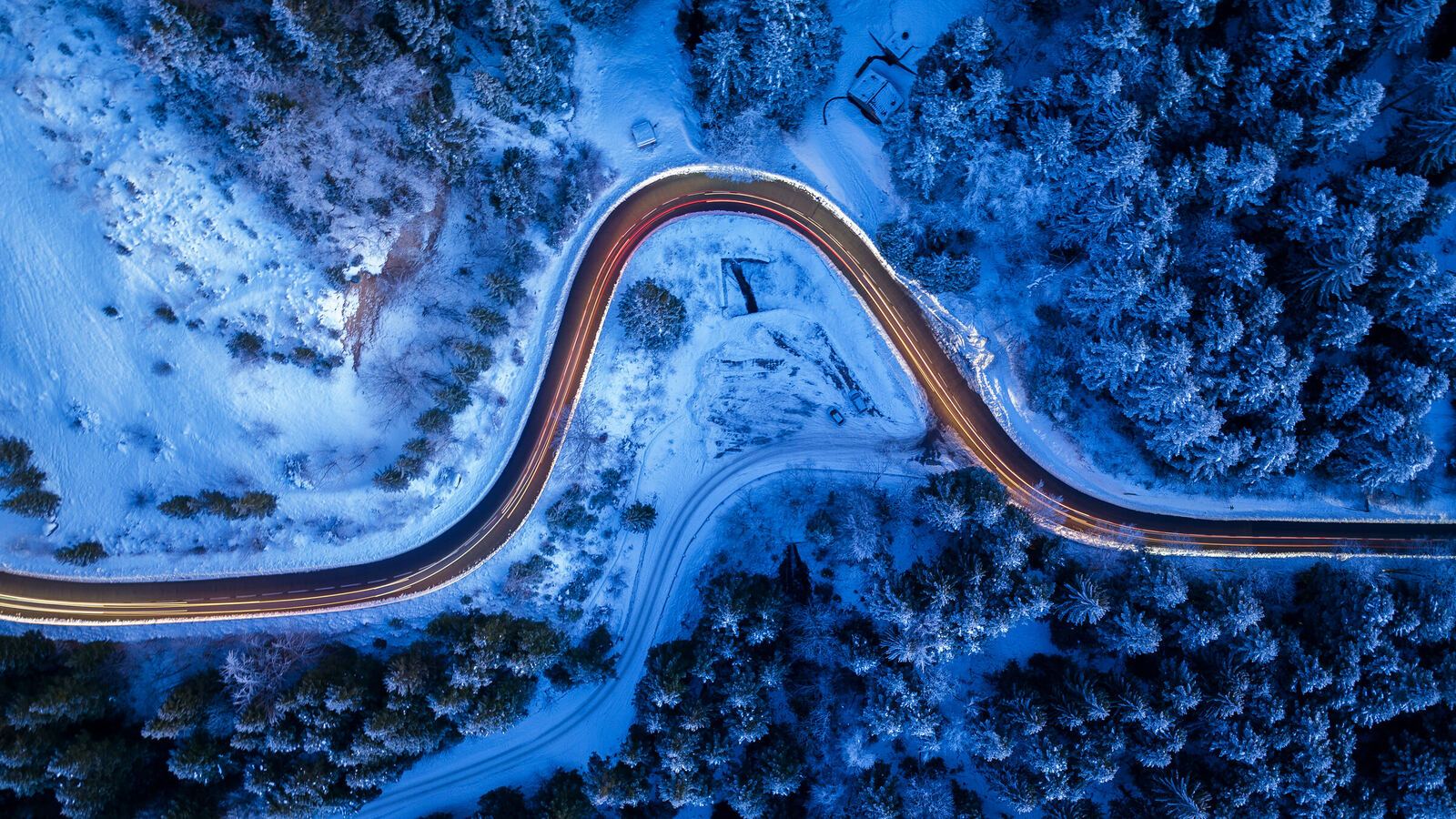 Route en lacets dans une forêt enneigée, vue du dessus